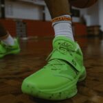green holo io shoe on court, close up